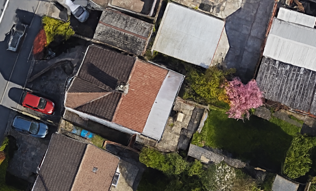 Aerial view of detached family home for transformation with red tiled roof and rear flat roof extension in Hale re-modelling project
